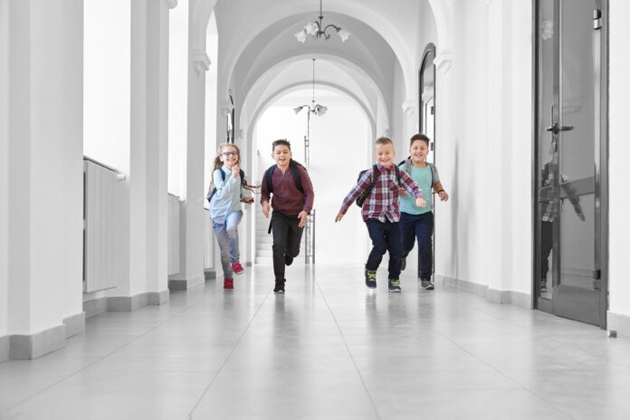 Pupils playing together and running on school corridor. Schooling